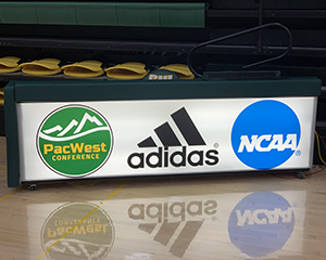 A graphic of 3 sponsors on the front of a scorer table